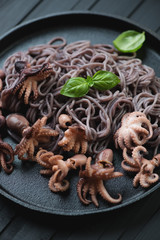 Close-up of octopuses with black rice noodles, selective focus