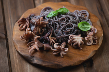 Fototapeta premium Black rice vermicelli with octopuses on a chopping board