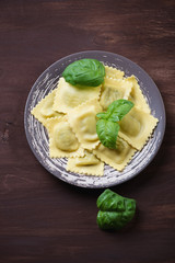 Above view of italian ravioli with basil, dark wooden background