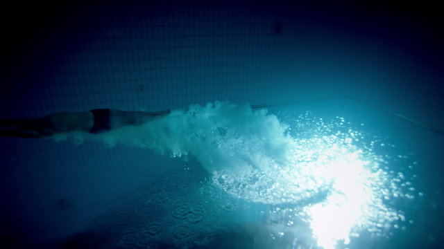 Underwater view of a professional male swimmer diving into deep blue water