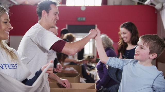 Cute young boy makes a charity donation and gets a high five from a volunteer - Powered by Adobe