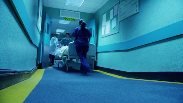 Hospital emergency team rush a patient on a gurney to the operating theatre