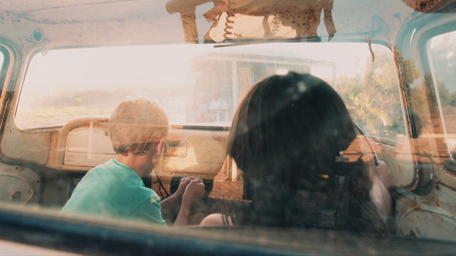 Children petending to drive an old vehicle on summer vacation