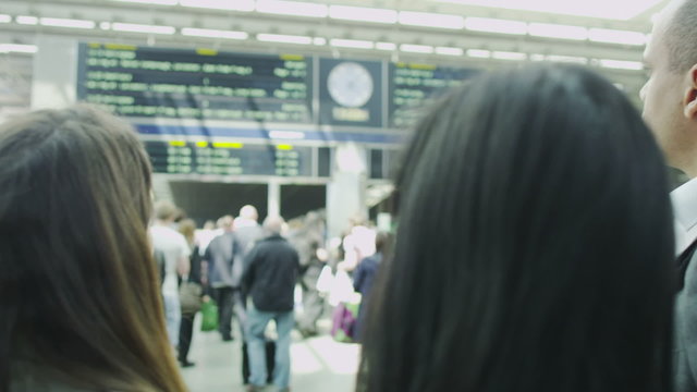 Young professionals looking at the departure boards at a busy railway station