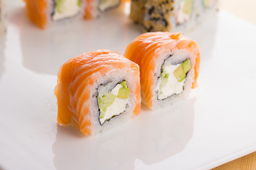 Sushi set on white plate over wooden background
