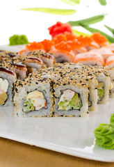 Sushi set on white plate over wooden background