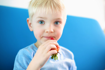 Truskawkowy chłopiec, chłopiec je owoc truskawki - obrazy, fototapety, plakaty