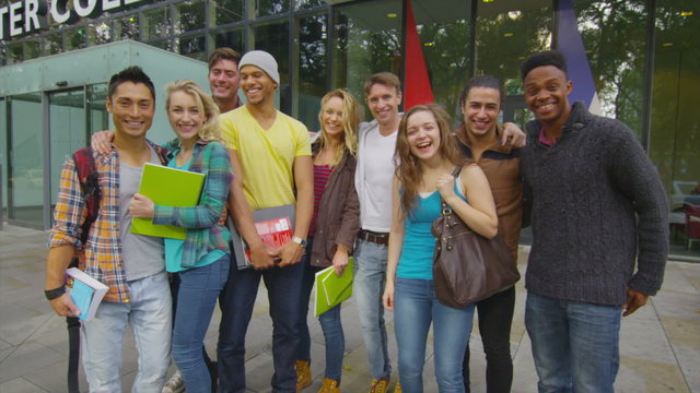 Portrait of cheerful diverse student group outside college building