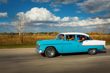 Fototapeta na wymiar Old classic car on street of Cuba with white clouds and blue sky