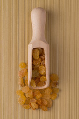 Wooden scoop with golden raisins