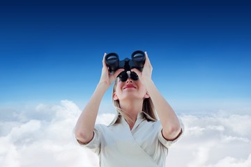 Composite image of businesswoman looking through binoculars