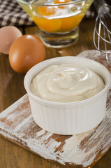 Mayonnaise in  bowl with eggs  on  wooden background