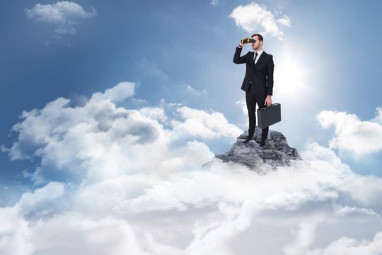 Businessman holding a briefcase while using binoculars