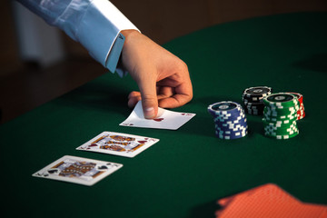 close-up of a man's hand opens the cards at a poker table with a