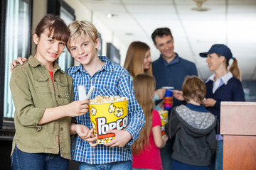 Affectionate Brother And Sister Holding Popcorn At Cinema