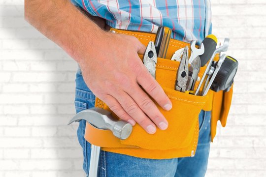 Composite image of midsection of handyman wearing tool belt