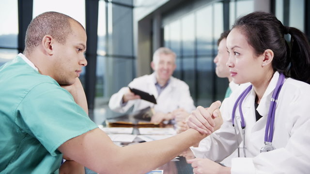 Bored doctor and nurse in a meeting challenge each other to arm wrestle