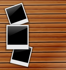 Three blank photo frames on wooden background