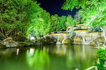 Fototapeta na wymiar Waterfall with light from lamp in night garden