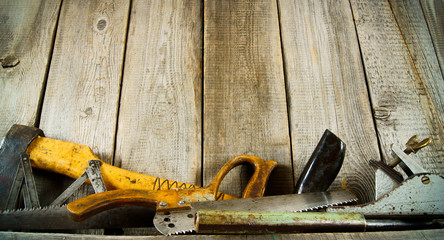 Many old tools ( axe, saw and others) on a wooden shelf.