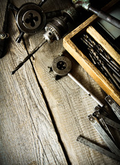 Old drill, a box with drills, pliers and ruler on wooden