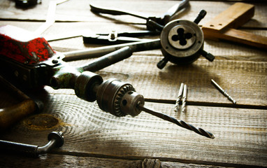 Old drill, compasses, ruler and drills on a wooden background.