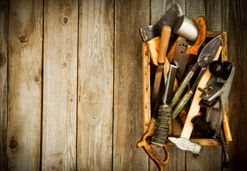 Old working tools in box on wooden background.