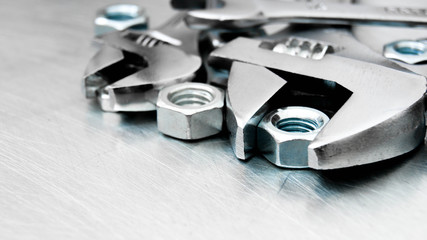 Wrenches and nuts on the scratched metal background.