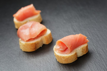 baguette slices with curred salmon on slate background