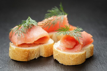 baguette slices with curred salmon and dill on slate background