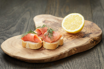 baguette slices with curred salmon and dill on wood table