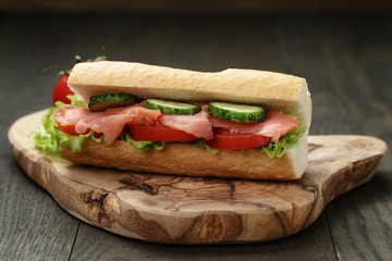 sandwich with salmon and vegetables on wood table