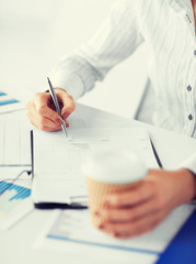 woman filling in blank paper and drinking coffee