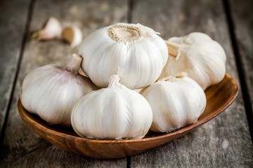 Organic garlics in the bowl on a wooden table