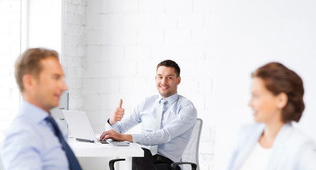 happy businessman showing thumbs up in office