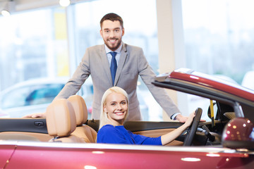 happy couple buying car in auto show or salon
