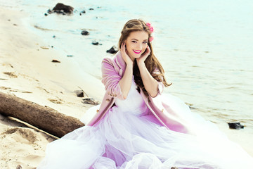 Beautiful young bride with pink roses on the beach