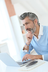 Naklejka premium Trendy mature man working from home with laptop
