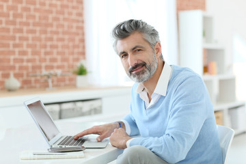 Trendy mature man working from home with laptop