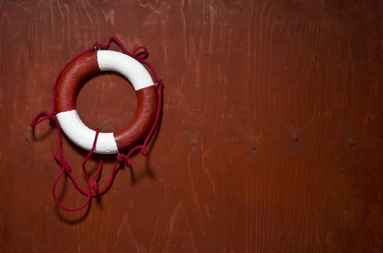 Red and white life buoy hanging on the side of a wood