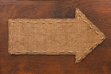 Arrow made of burlap lies on a wooden background