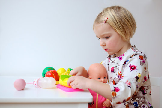 Toddler girl playing with doll at home or kindergarten