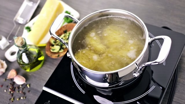 Cooking organic pasta with garlic herbs and parmesan cheese.
