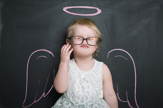 Little girl at the blackboard with wings and halo