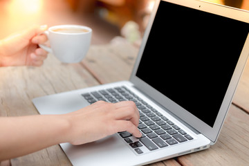 Closeup of business woman hand typing on laptop keyboard and cof