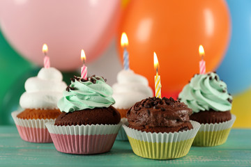 Delicious birthday cupcakes on table on bright background