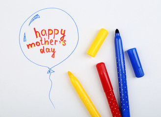 Happy Mothers Day message written on paper and markers close up