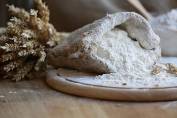 Flour in burlap bag on cutting board and wooden table