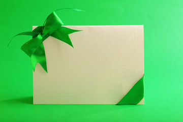 Card decorated with bow on green background