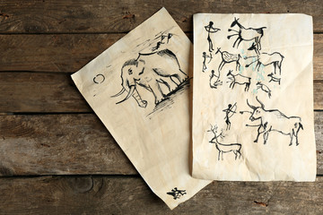 Rock paintings on paper on wooden background